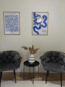 duas cadeiras e um vaso numa mesa num quarto em Gjirokastra Design Apartments em Gjirokastër