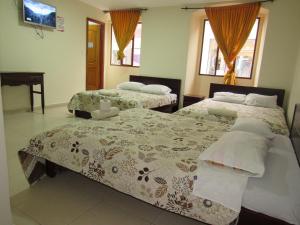 a bedroom with two beds and a tv and two windows at HOTEL COLONIAL in Ipiales