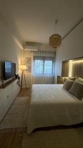 a bedroom with a large white bed and a window at Gjirokastra Design Apartments in Gjirokastër