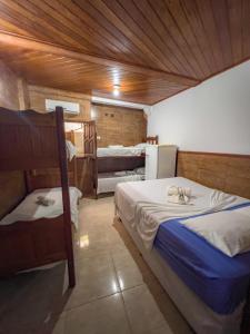 1 dormitorio con 2 camas en una habitación con techos de madera en pousada Vitoria, en Morro de São Paulo