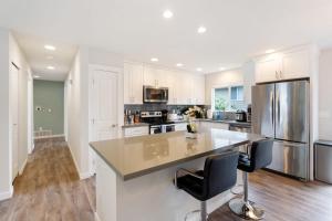 a kitchen with white cabinets and a large island with chairs at Kubota Family Home BY Betterstay in Seattle