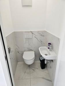 Baño blanco con aseo y lavamanos en 3 Zimmer Wohnung, en Maria Lanzendorf