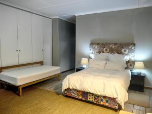 1 dormitorio con cama y banco. en Mitchell Guesthouse, en Pietermaritzburg