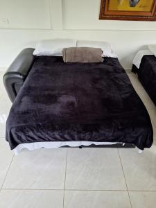 a bed with a black blanket on top of it at Backyard loft in the heart of the forest in Salento