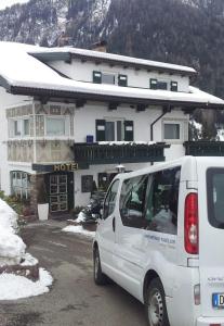 ein weißer Van vor einem Hotel geparkt in der Unterkunft Chalet Hotel Hartmann - Adults Only in St. Ulrich in Gröden