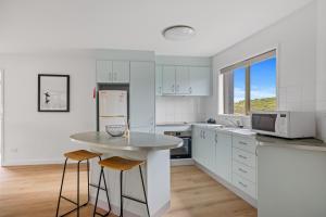 a kitchen with white cabinets and a table with stools at Sandy Point Beach Escape 1 Bedroom Apartment in Sandy Point