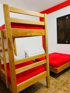 2 Etagenbetten in einem Zimmer mit einer roten Matratze in der Unterkunft Finca Hotel Calle Jardin in La Tebaida
