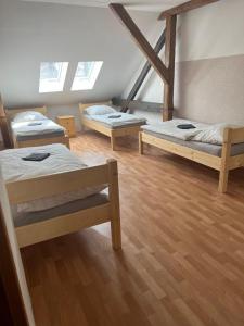3 camas en una habitación con suelo de madera en Apartmány Zahradní, en Františkovy Lázně