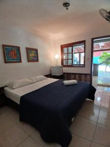 a bedroom with a large bed and two windows at Pousada das Palmeiras in Garopaba