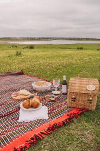 una coperta da picnic con bicchieri da cibo e vino e un cesto di Casa Coração Alentejano- Casas com EnCanto a Reguengos de Monsaraz