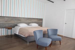a bedroom with a bed and two blue chairs at Basadre Apart Hotel in Tacna