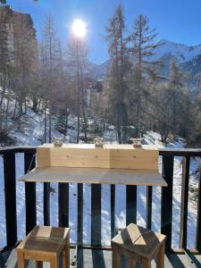 a table and two stools on a balcony with snow at Les Orres 1650 Résidence l'Oustal in Les Orres