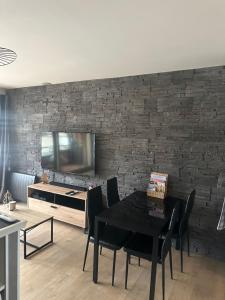 a dining room with a table and a tv on a brick wall at Metabief- Front de piste in Métabief