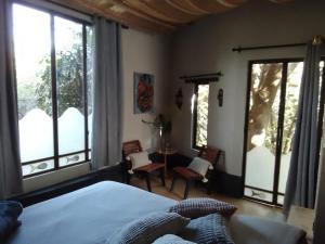 een slaapkamer met grote ramen en een bed en een tafel bij Yolitia Wellness in Malinalco
