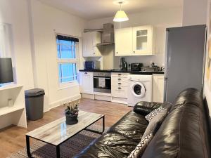 a living room with a leather couch and a kitchen at Yeovil Apartments in Yeovil