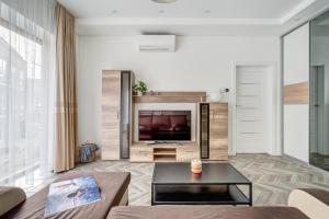 ein Wohnzimmer mit einem Sofa und einem TV in der Unterkunft cohost I New Bastėja Life Apartments w-Garage Prkg & Self Check-in in Vilnius