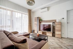 a living room with a couch and a television at cohost I New Bastėja Life Apartments w-Garage Prkg & Self Check-in in Vilnius