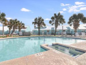 a large swimming pool with palm trees in the background at Bayfront Kontiki 704 in Rockport