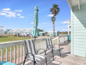 a patio with two chairs and an umbrella at Bayfront Kontiki 704 in Rockport