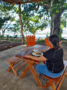 una mujer sentada en una mesa con un plato de comida en Cabañas piedra grande ometepe, en Altagracia