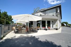 a patio with tables and chairs and an umbrella at Hotel Perłowy in Okuninka