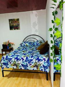 a bedroom with a bed with a blue floral comforter at EL EDEN HABITACIONES in Manizales