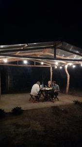 un grupo de personas sentadas en una mesa por la noche en Cabañas piedra grande ometepe, en Altagracia