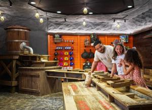 Un homme et deux filles regardent des tables en bois dans l'établissement Great Wolf Lodge Manteca, à Manteca