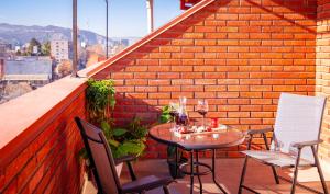 a table and chairs on a balcony with a brick wall at Rivendell Boutique By Umbrella in Tbilisi City