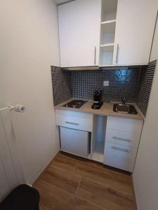 eine kleine Küche mit weißen Schränken und einer Spüle in der Unterkunft Studio au centre des 4 vallées in Nendaz