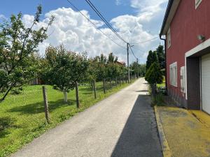 an empty road next to a red building with trees at 朋来house in Ledine