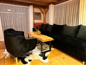 a living room with a black couch and a table at Gospodarstwo Agroturystyczne Baciary DOMEK W GORACH in Klikuszowa