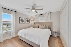 ein weißes Schlafzimmer mit einem Bett und einem Deckenventilator in der Unterkunft Bon Vie in Gulf Shores
