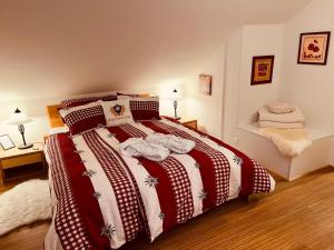 a bedroom with a bed with a red and white blanket at Engel Ingold Lodge Chalet "Bärgblümli" in Habkern