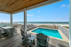 une terrasse avec une piscine, des chaises et une plage dans l'établissement Brown By The Beach, à Orange Beach