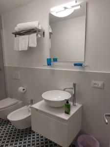 W łazience znajduje się umywalka, toaleta i lustro. w obiekcie Casa Vacanze Aenaria-Ristrutturato 2024 w mieście Ischia