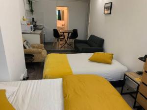 een kamer met 2 bedden met gele lakens en een keuken bij Chez Alam à L'opéra de Lyon in Lyon