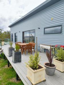 a deck with potted plants and a table and a house at Fingerpost Hill Farm Stay in Campania