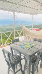 a table and chairs on a porch with a hammock at Hermosa cabaña privada cerca a Tulua con jacuzzi in La Carmine