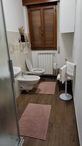 une salle de bain avec deux lavabos et un WC et deux tapis dans l'établissement La Beccaccia, à Baceno