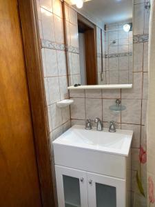 W łazience znajduje się biała umywalka i lustro. w obiekcie Cabaña Camila w mieście El Bolsón