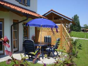 a table and chairs under an umbrella in a garden at Ferienwohnung Am Wundergraben inkl. Chiemgaukarte in Ruhpolding +8 photos