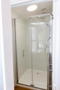 La salle de bains est pourvue d'une douche avec une porte en verre. dans l'établissement Smart Modern Studio With Free Parking, Wifi, Close To Town, Hospital, Uni, Quiet Area, Contact For Best Prices, à Exeter