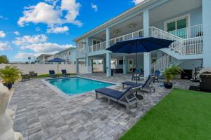 a house with a swimming pool with chairs and an umbrella at Mermaid's Paradise ~ Pool ~ Dock ~ Games ~ Views in Marathon