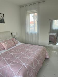 Cama rosa en habitación blanca con ventana en Casa M&N, en Thiene