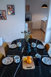 una mesa negra con platos, tazones y naranjas. en Magnifique Appartement de 3 chambres, en Annecy