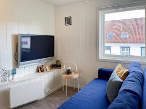 ein Wohnzimmer mit einem blauen Sofa und einem TV in der Unterkunft Stavanger BnB Ap5 by Berti’s in Stavanger
