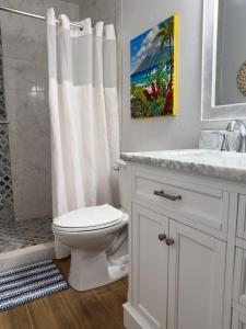 a white bathroom with a toilet and a shower at Kihei Bay Surf 130- Garden View Studio, FREE PARKING in Kihei