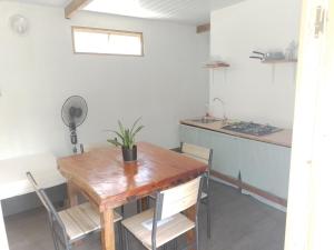 a dining room with a wooden table and a kitchen at TEMAEVA LODGE in Nuku Hiva
