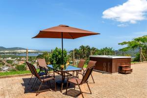 a table and chairs with an umbrella on a patio at Mansão Linda Vista Lagoa da Conceição Jacuzzi in Florianópolis